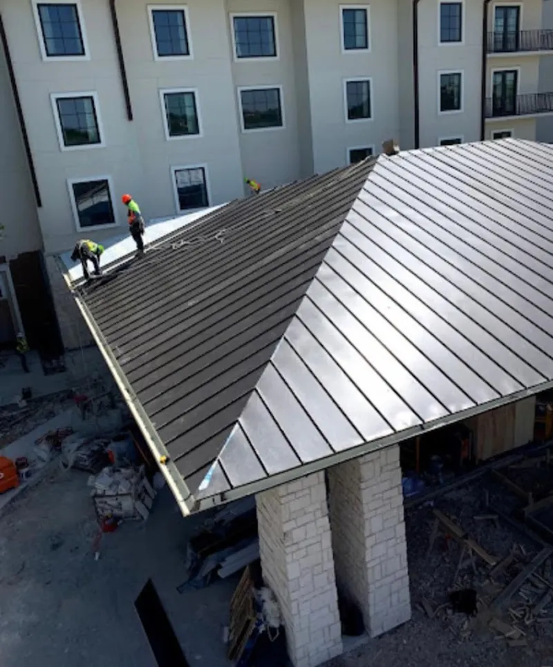 Crew installing standing seam metal roof panels on a commercial project in Gardere